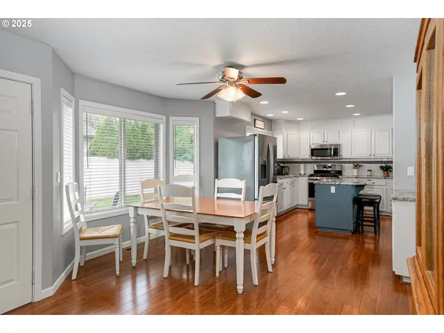 a dining room with furniture wooden floor and a kitchen view