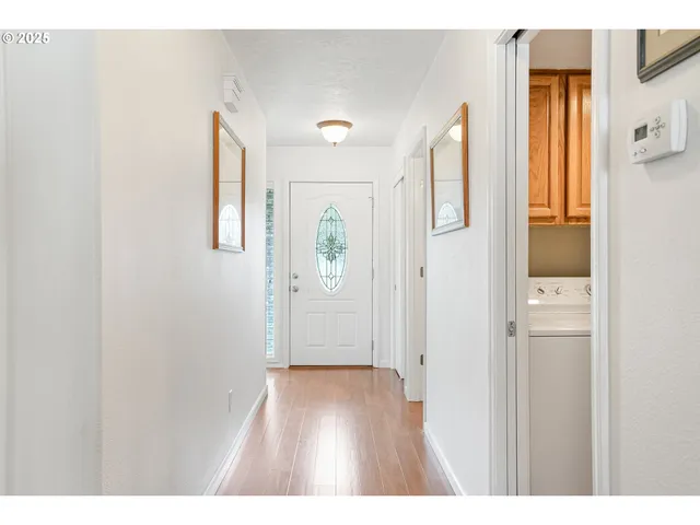 a view of an empty room with wooden floor and a bathroom