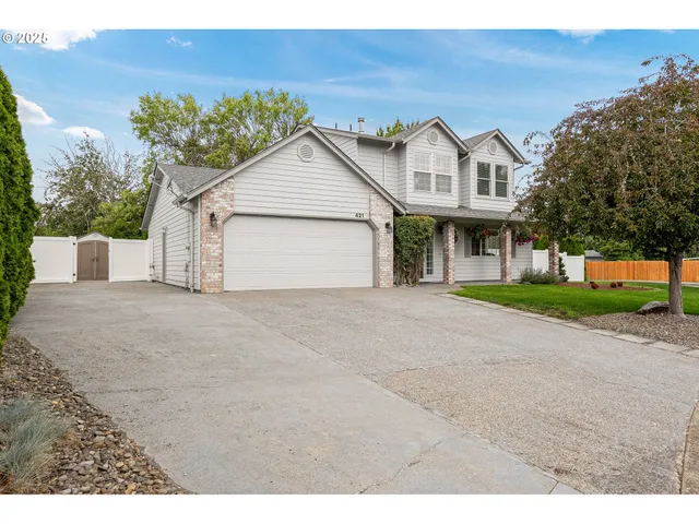a view of a white house with a small yard and large tree