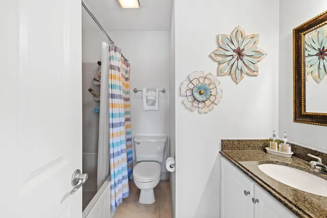 a bathroom with a granite countertop sink a toilet and a shower