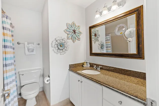 a bathroom with a granite countertop sink mirror vanity and toilet