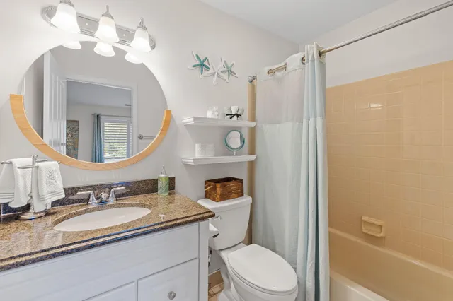 a bathroom with a granite countertop sink toilet a mirror a vanity and shower