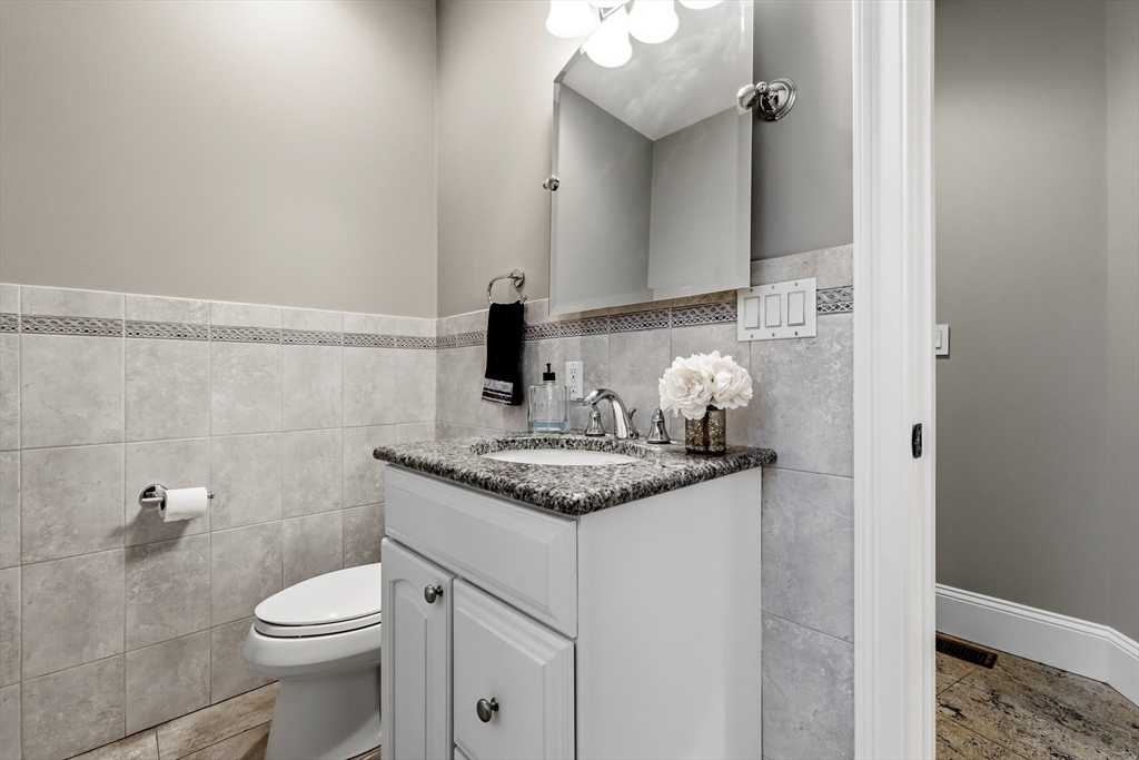 7 Freeman Street Lynnfield, MA 01940 - Photo 13 of 39 a bathroom with a granite countertop sink a toilet and a mirror