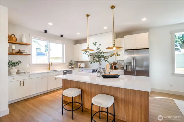 a kitchen with stainless steel appliances granite countertop a sink a stove a dining table and chairs