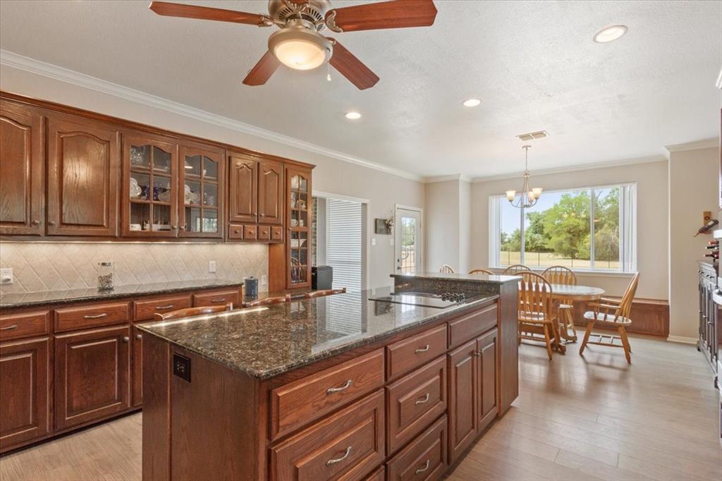 111 Spring Creek Street Waco, TX 76705 - Photo 18 of 40 Spacious kitchen featuring wood-finish cabinetry, dark stone countertops, a large kitchen island, and recessed lighting