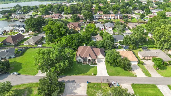 a view of a house next to a big yard and large trees