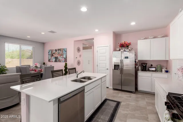 a kitchen that has a refrigerator a stove a sink dishwasher a dining table and chairs with wooden floor