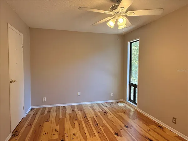a view of an empty room and window and chandelier fan