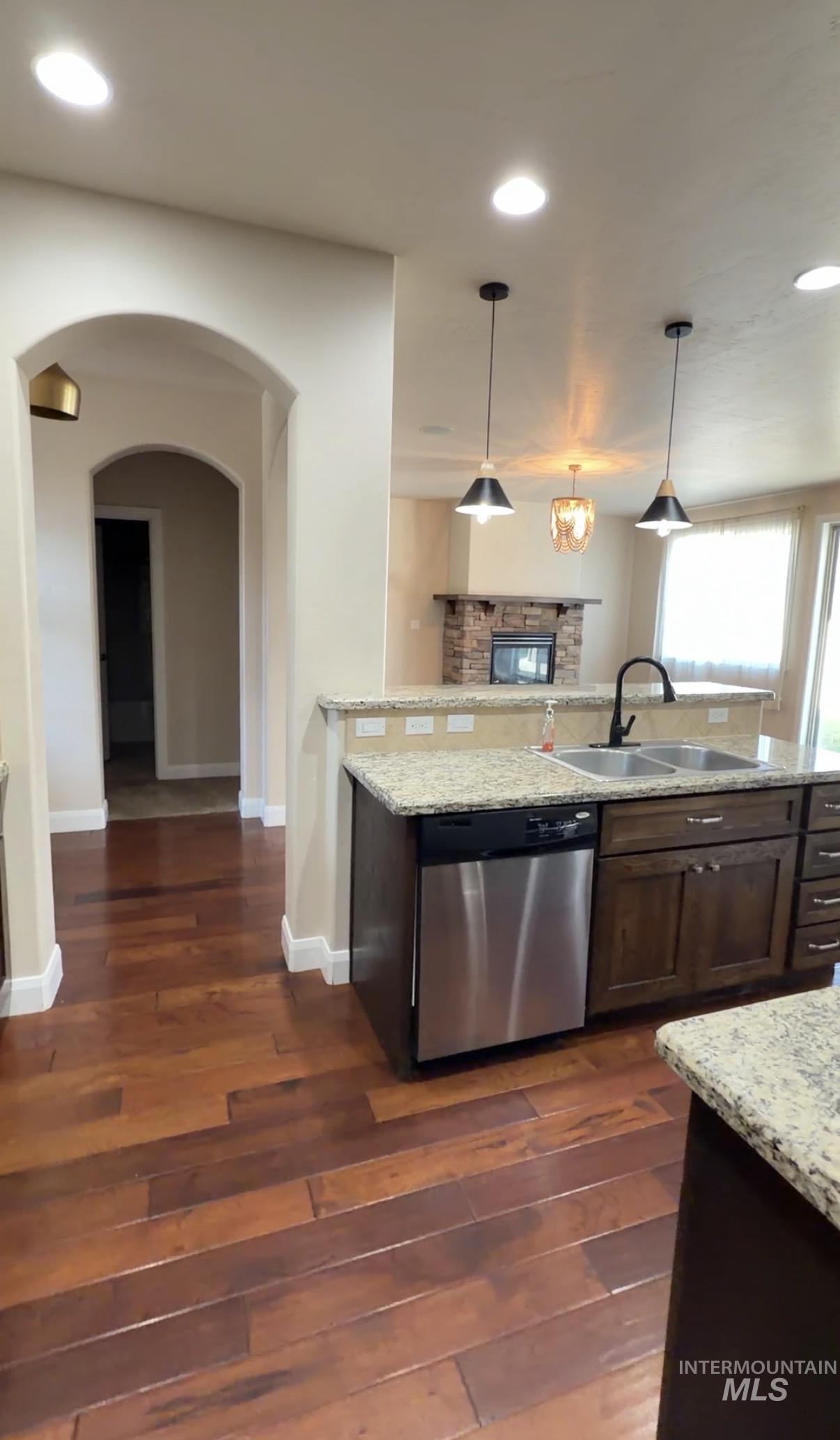 4678 North Elmstone Avenue Meridian, ID 83646 - Photo 4 of 15 Kitchen with hanging light fixtures, arched walkways, light stone counters, recessed lighting, and dishwasher