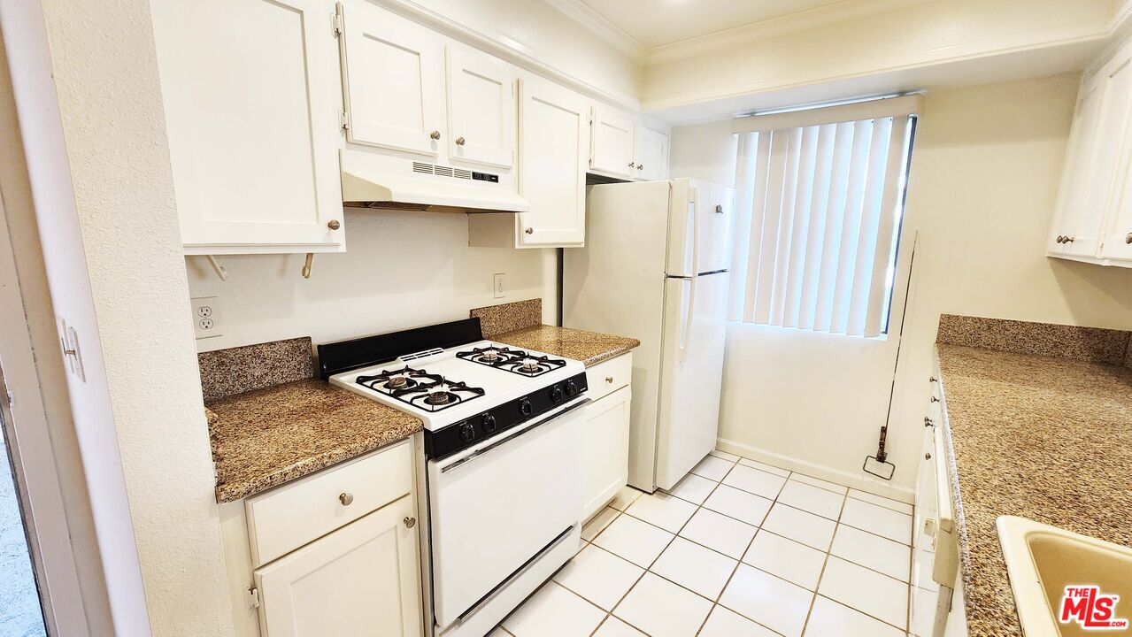 1425 West 12th Street, Unit 161 Los Angeles, CA 90015 - Photo 3 of 19 a kitchen with granite countertop a stove a refrigerator and cabinets