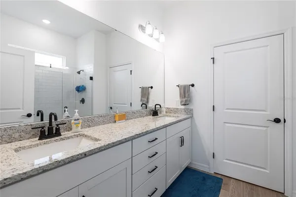a bathroom with a granite countertop double vanity sink mirror and