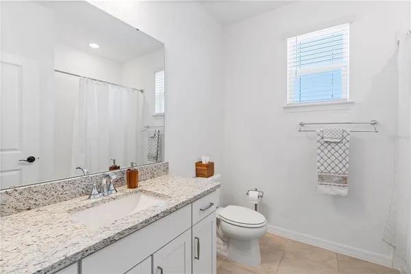 a bathroom with a granite countertop sink toilet and mirror