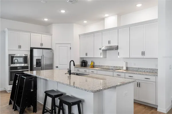 a kitchen with kitchen island granite countertop a sink stove and refrigerator