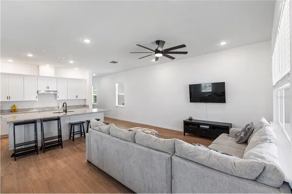 a living room with furniture a flat screen tv and kitchen view