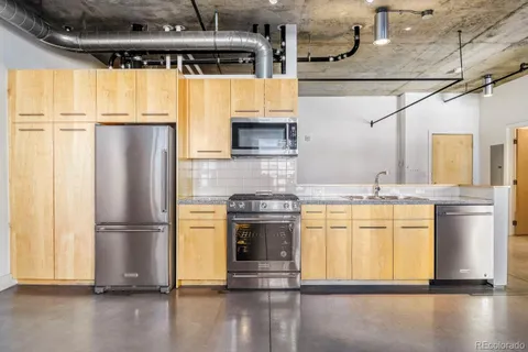 a kitchen with stainless steel appliances granite countertop a refrigerator a stove and a sink with wooden floor