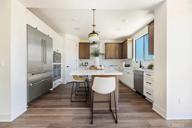 a kitchen with cabinets wooden floor dining table and stainless steel appliances