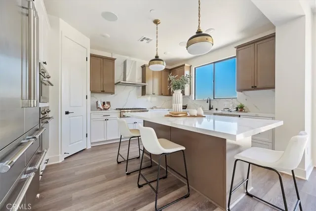 a kitchen with stainless steel appliances granite countertop a sink a stove a refrigerator and island with wooden floor