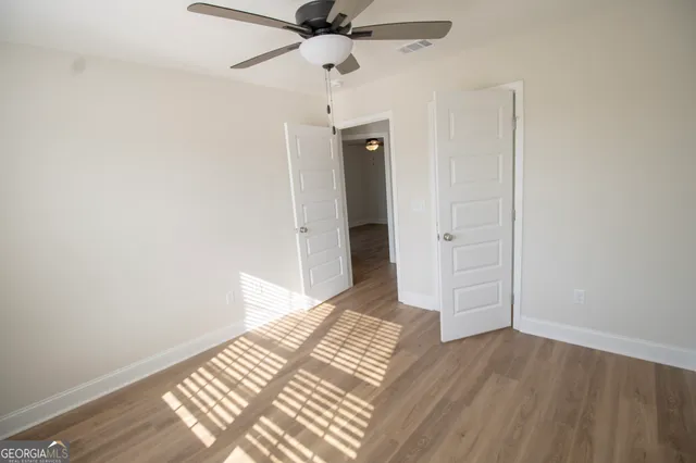 an empty room with wooden floor closet and windows