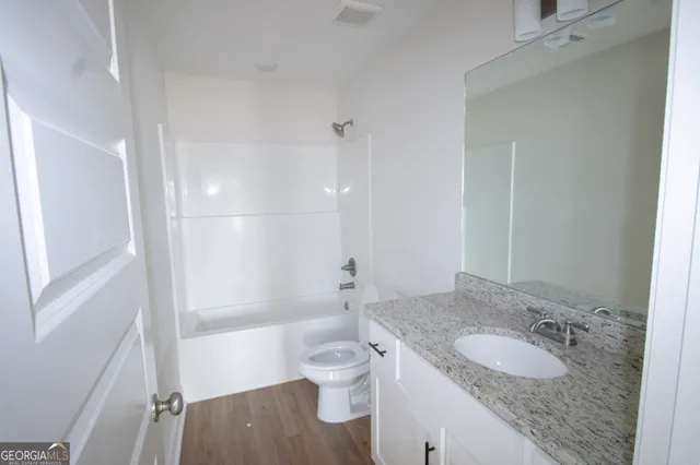 a bathroom with a granite countertop sink a toilet and shower