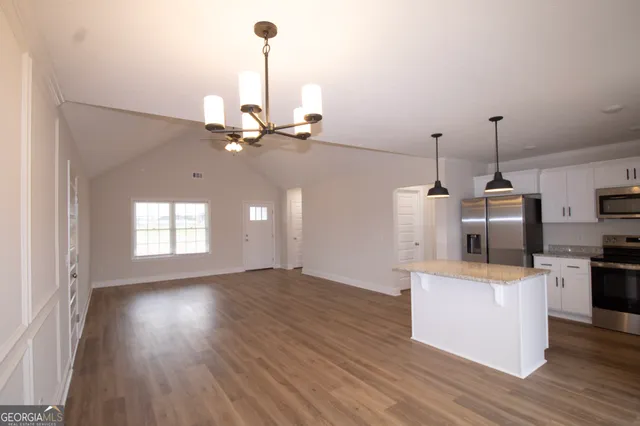 a view of a kitchen with stainless steel appliances granite countertop a stove and wooden floor