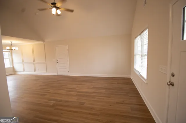 a view of an empty room with wooden floor and a window
