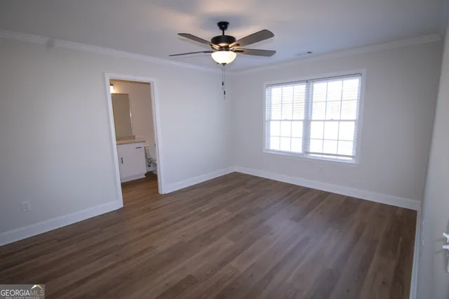 an empty room with wooden floor and ceiling fan