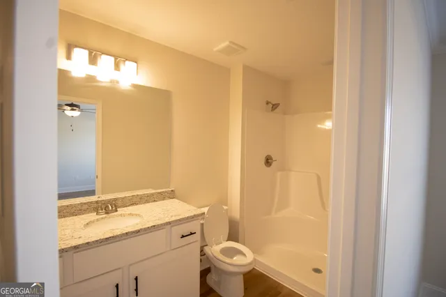 a bathroom with a granite countertop sink toilet and shower