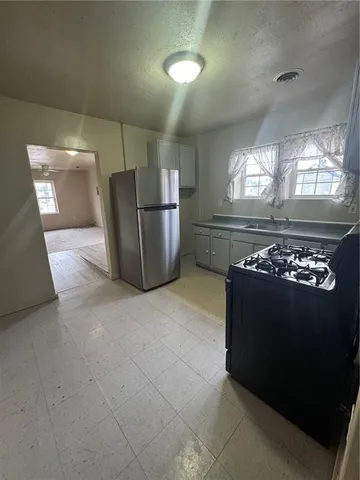 a view of a refrigerator in kitchen and an empty room