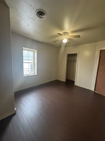 a view of empty room with wooden floor and fan