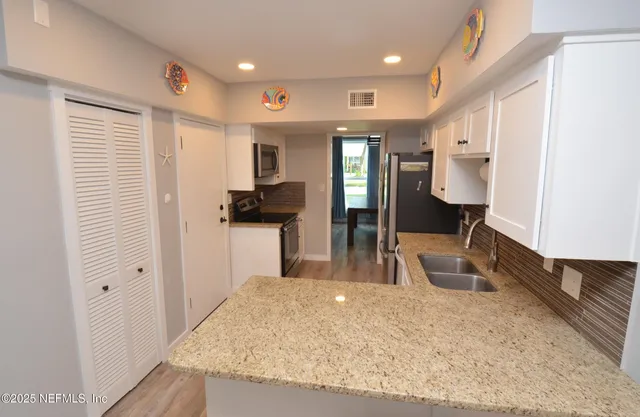 a kitchen with stainless steel appliances granite countertop sink stove refrigerator and cabinets