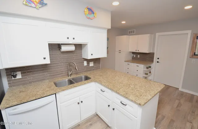 a kitchen with granite countertop a sink a stove and cabinets