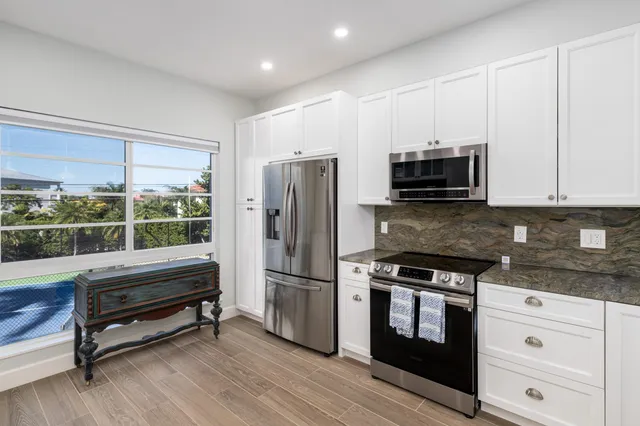 a kitchen with kitchen island granite countertop a refrigerator and a stove top oven