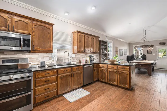 a kitchen with stainless steel appliances granite countertop wooden cabinets a stove a sink and a microwave