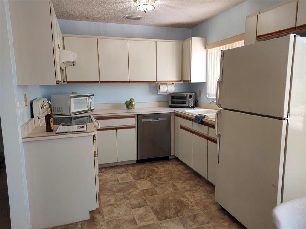 47 Lake Forest Place, Unit 47 Palm Coast, FL 32137 - Photo 10 of 12 a kitchen with white cabinets and white appliances