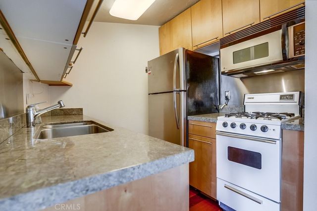 a kitchen with stainless steel appliances granite countertop a refrigerator a stove and a sink with wooden floor