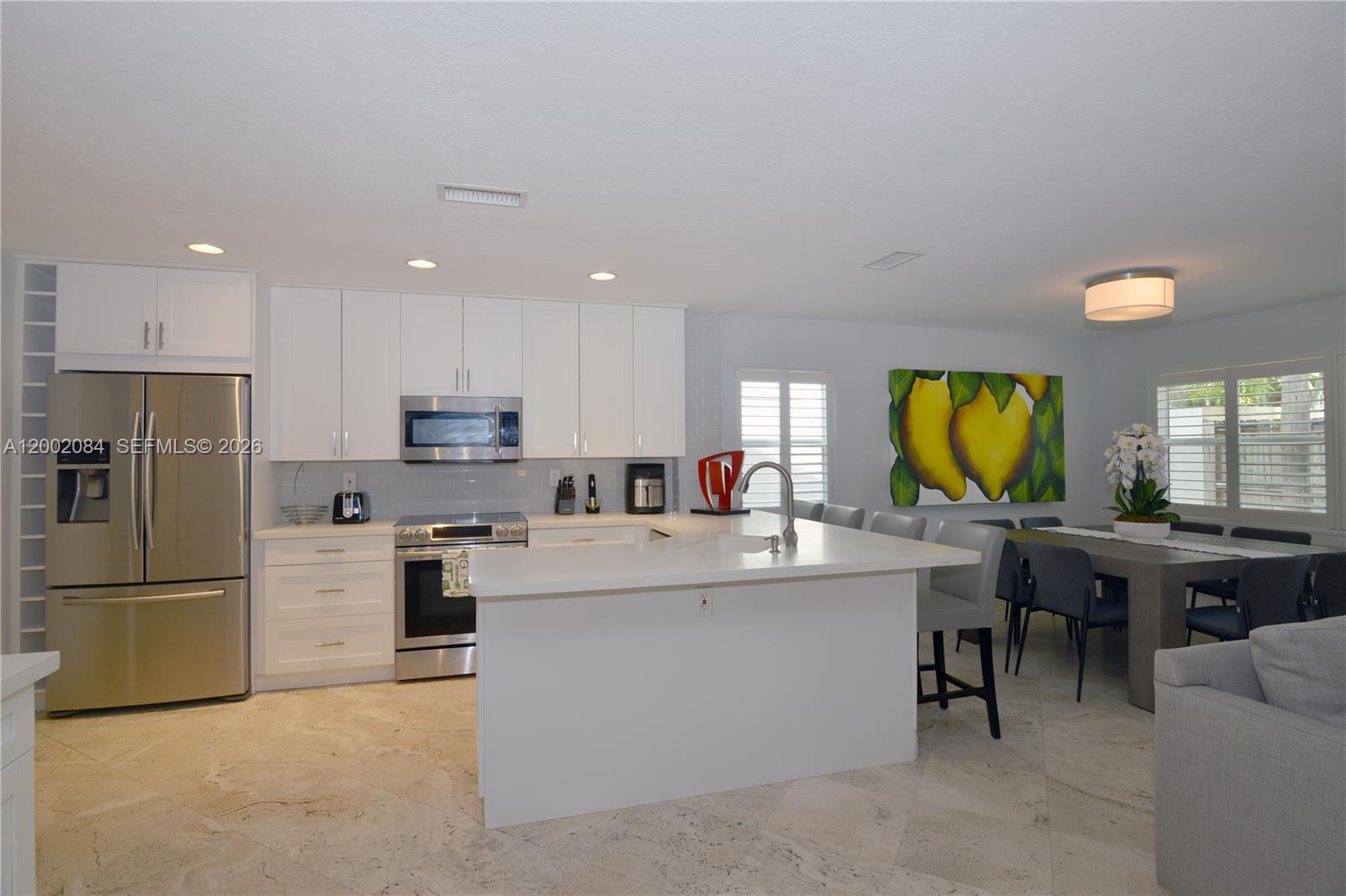 3081 Matilda Street, Unit A Miami, FL 33133 - Photo 5 of 14 a kitchen with stainless steel appliances kitchen island granite countertop a refrigerator a stove a sink a dining table and chairs