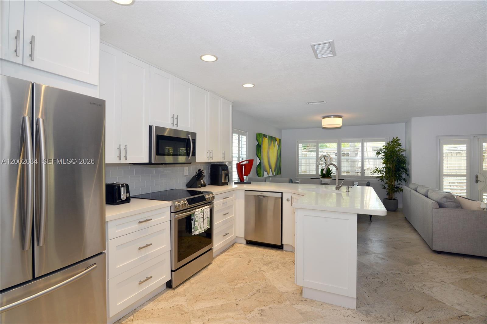 3081 Matilda Street, Unit A Miami, FL 33133 - Photo 6 of 14 a kitchen with white cabinets and stainless steel appliances