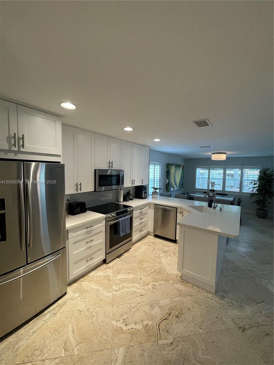 3081 Matilda Street, Unit A Miami, FL 33133 - Photo 7 of 14 a kitchen with kitchen island a counter top space stainless steel appliances and cabinets