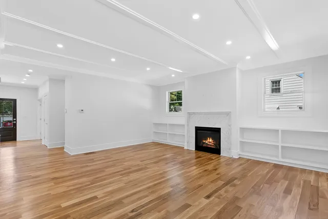 an empty room with wooden floor fireplace and windows