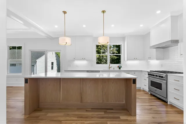 a kitchen with stainless steel appliances granite countertop a stove a sink a center island and a wooden floor