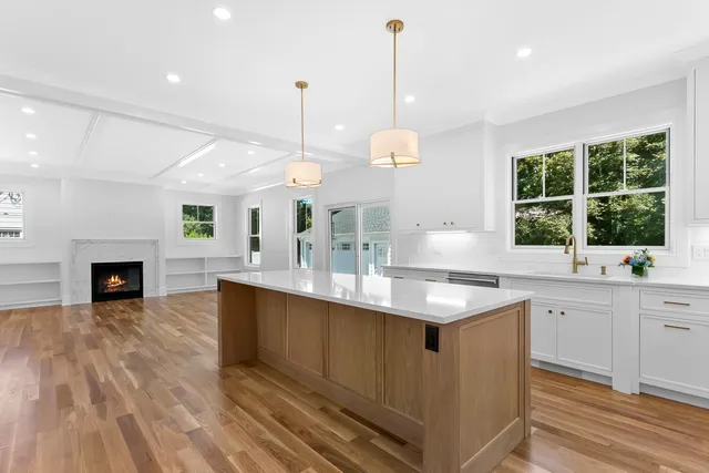 a kitchen with kitchen island granite countertop a sink a counter top space appliances and a fireplace