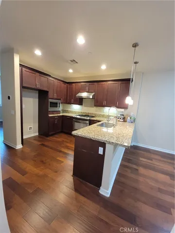 a kitchen with kitchen island a stove a refrigerator and a microwave oven with wooden floor