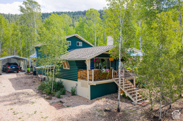 714 Spotted Fawn Way Kamas, UT 84036 - Photo 1 of 34 View of front of property featuring faux log siding, a detached carport, driveway, a forest view, and a chimney