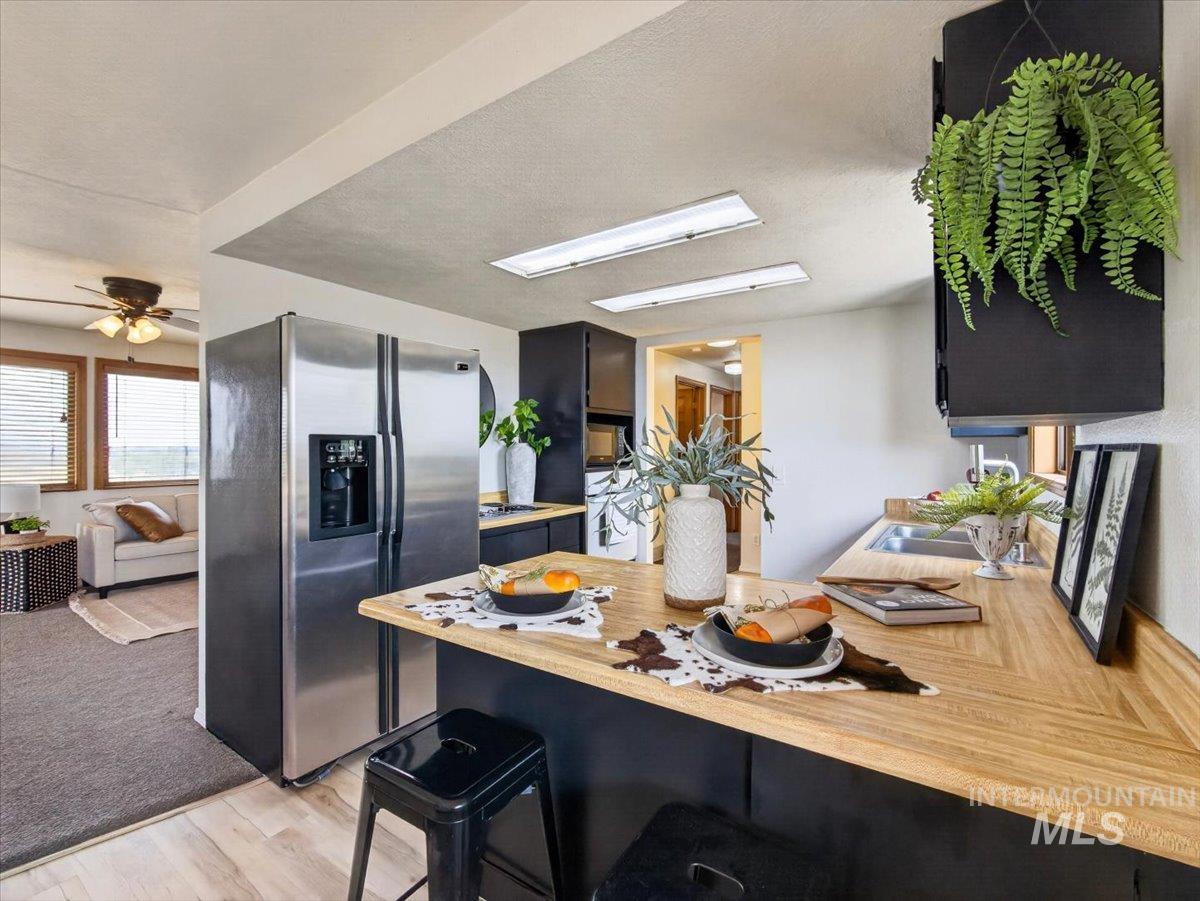 8989 Hillview Road Emmett, ID 83617 - Photo 16 of 50 Kitchen featuring wood-finish countertops, black cabinetry, and a stainless steel refrigerator