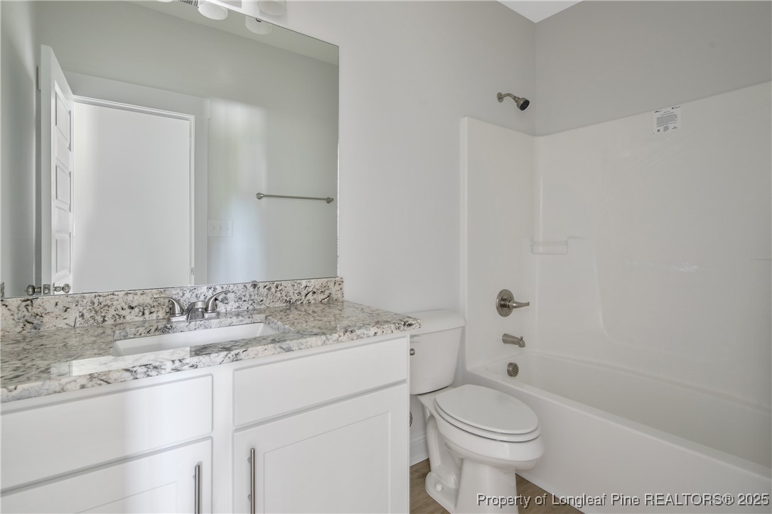 4905 High Branch Court Stedman, NC 28391 - Photo 35 of 47 a bathroom with a granite countertop toilet a sink and a bathtub