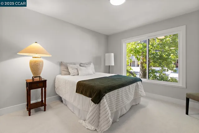 a bedroom with a bed lamp on table and a window