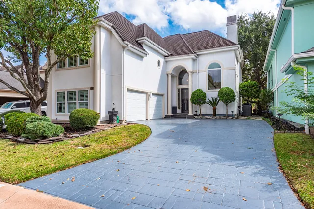 a view of a white house with a small yard plants and a large tree