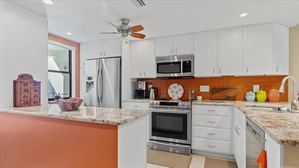 a kitchen with granite countertop a stove top oven microwave and refrigerator