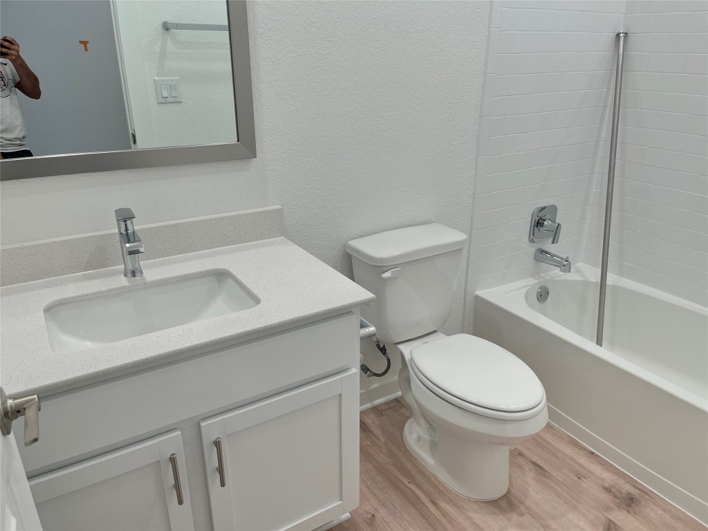 2012 Bobtail Pass Leander, TX 78641 - Photo 14 of 22 Full bathroom with a textured wall, washtub / shower combination, vanity, and light wood-style floors