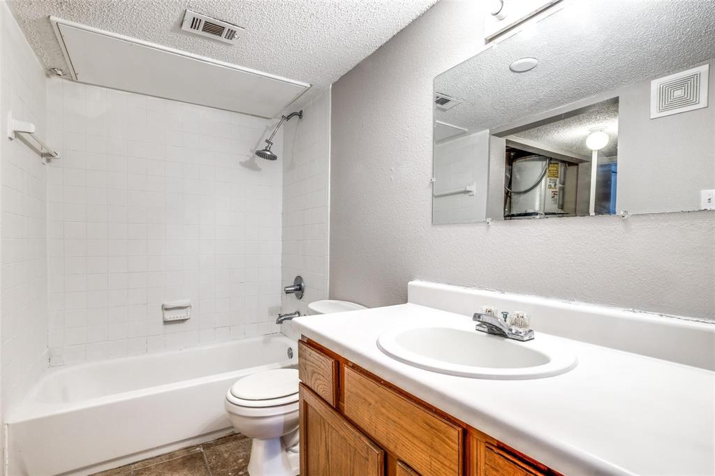 6108 Abrams Road, Unit 118 Dallas, TX 75231 - Photo 7 of 16 White tiled shower/tub combination with a chrome showerhead